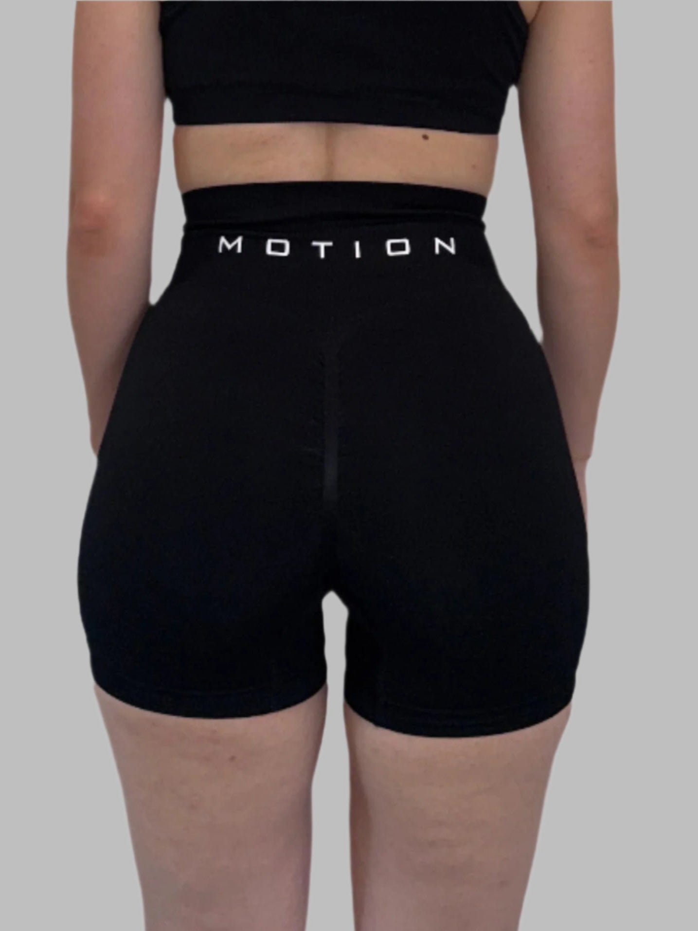 Black athletic shorts with 'MOTION' branding on a white background